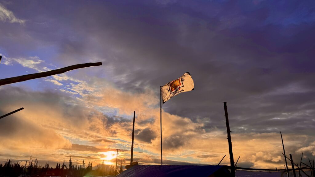 The golden hues from the setting sun created a breathtaking scene at the camp as the last remnants of the storm drifted away, leaving behind a sky filled with clouds illuminated in soft oranges and purples.