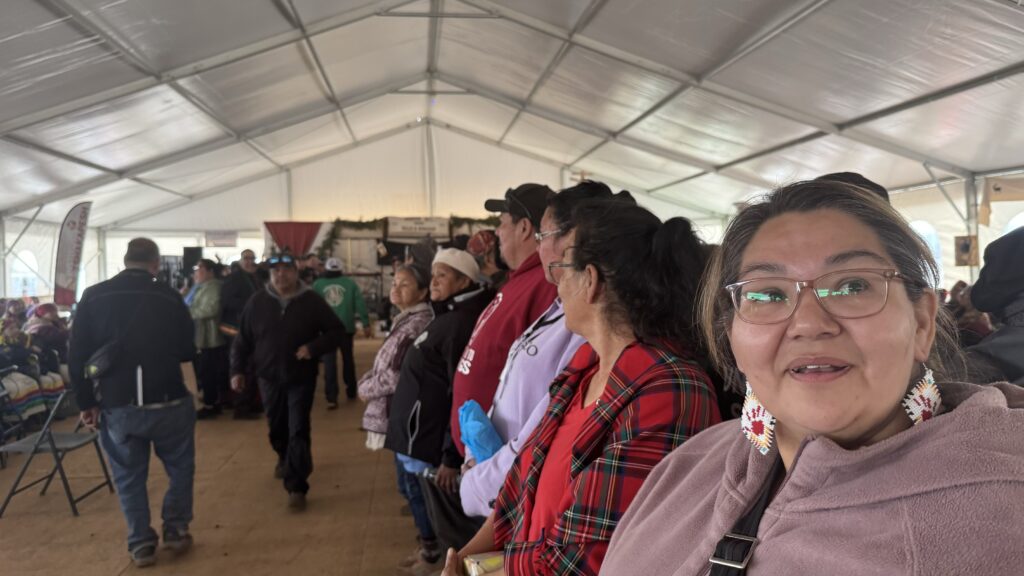 The third image captures a line of people inside the tent, preparing to participate in a gift exchange. The woman in the foreground, wearing glasses and beaded earrings, looks toward the camera with excitement, while the rest of the group is focused on the event.