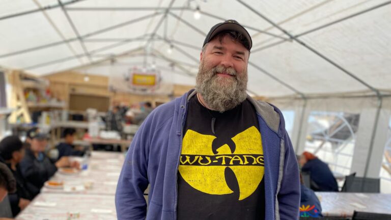 Me in a cap and Wu-Tang Clan t-shirt, smiling under a white tent